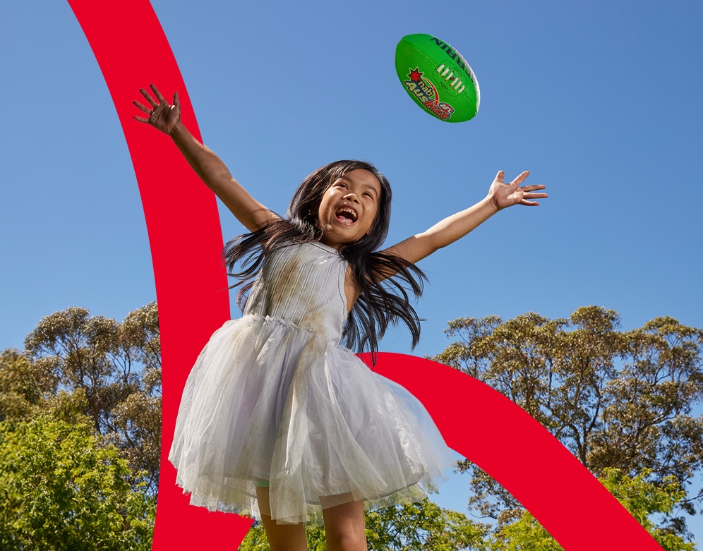 Young girl with AFL football taking a mark - Auskick.
